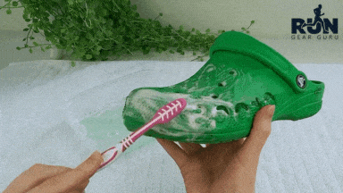 A girl cleaning green crocs with a toothbrush