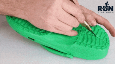 A man cutting green crocs into half